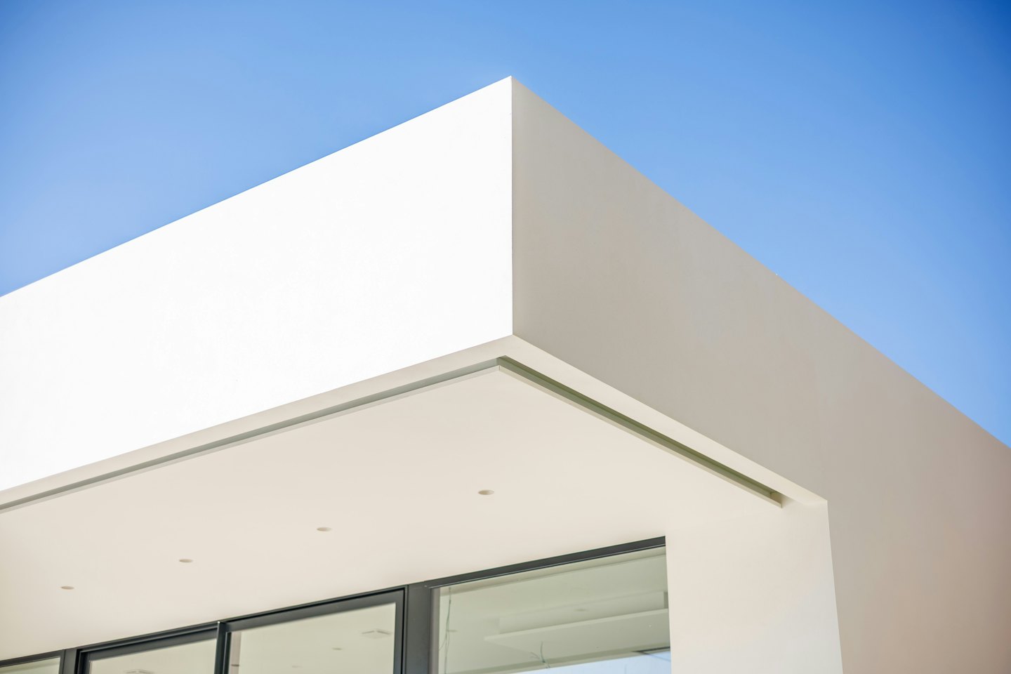 Edificio moderno bianco con grandi vetrate su cielo azzurro.