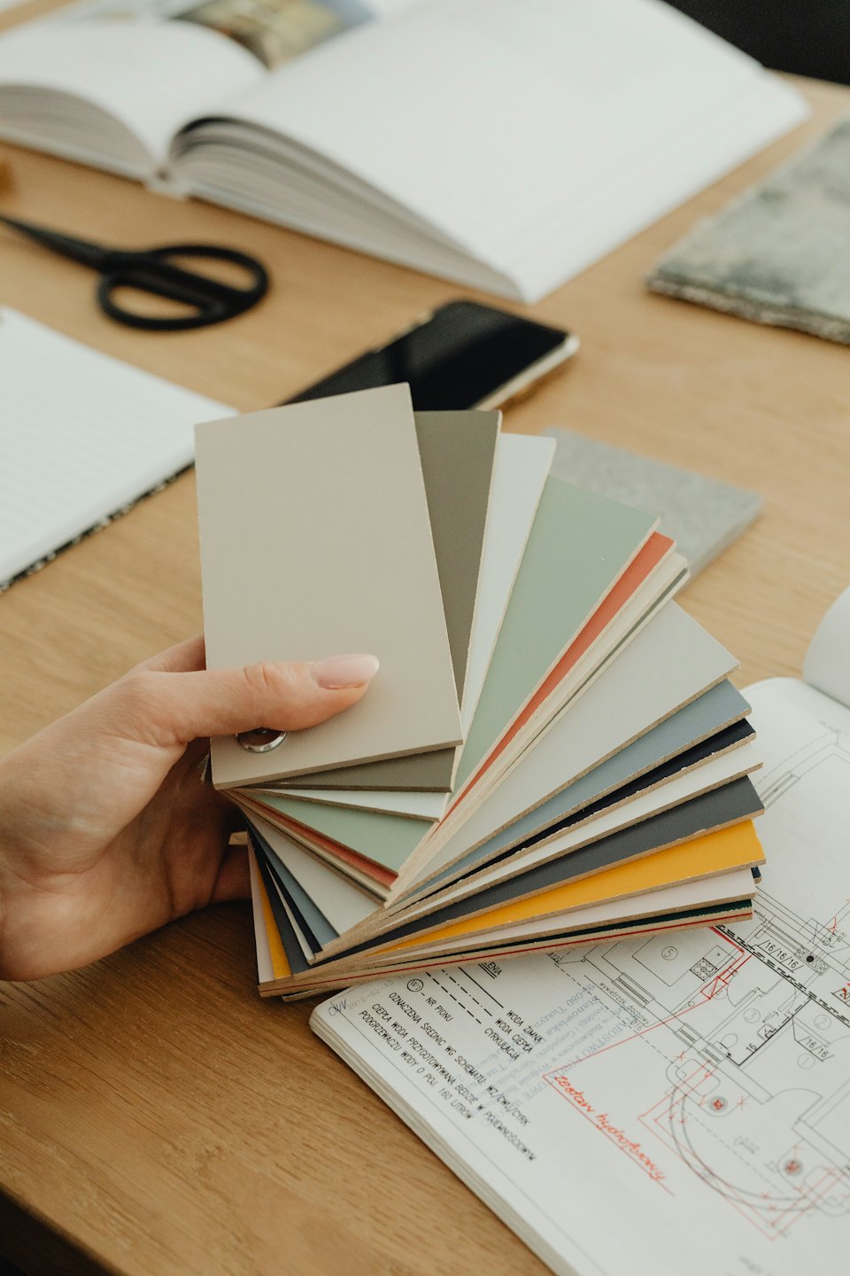 Mano che sceglie campioni di colore e materiale su una scrivania.