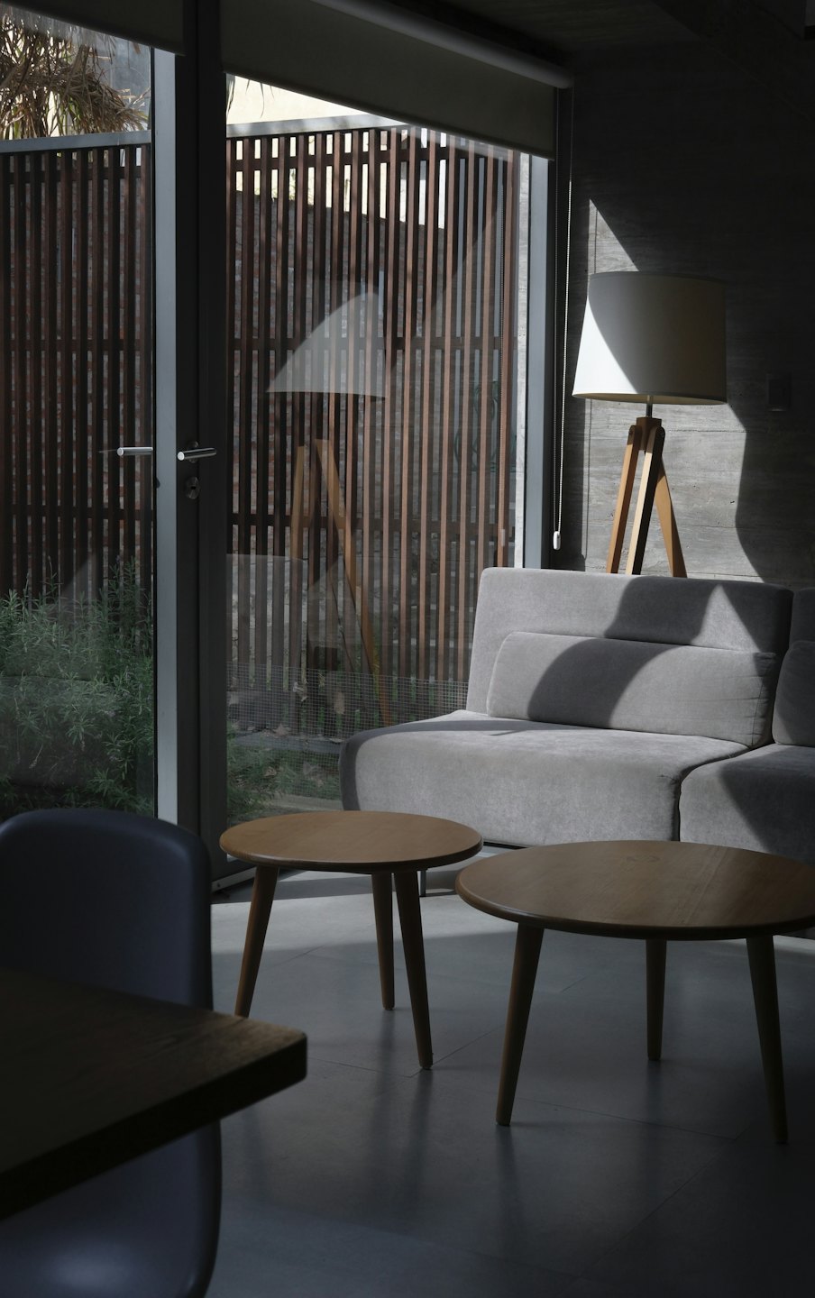 Soggiorno minimalista con divano grigio e tavolini in legno.