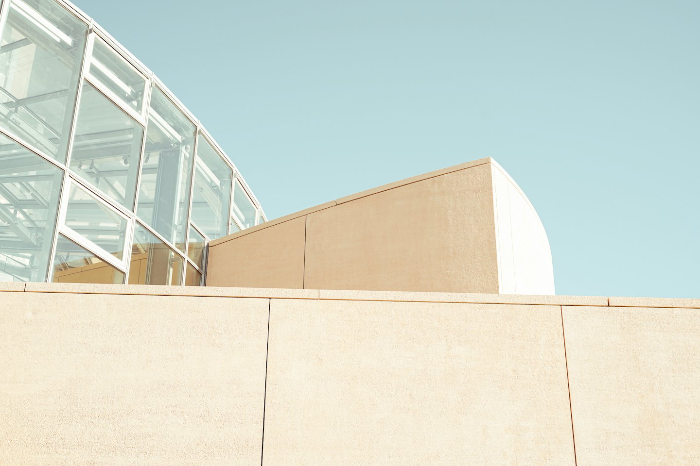 Edificio moderno color beige con sezione curva e grandi vetrate.