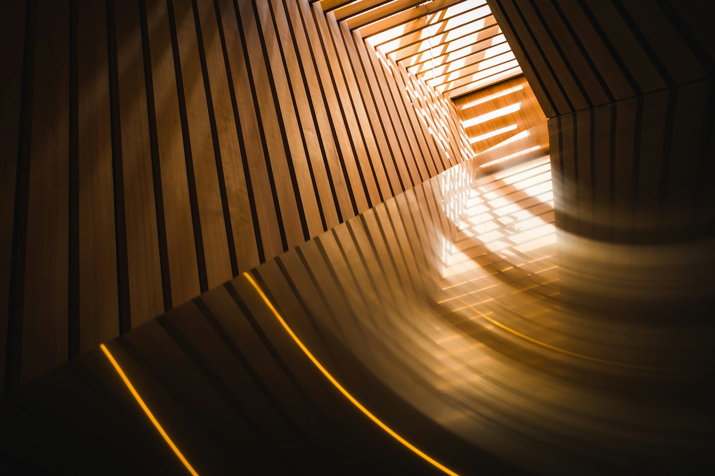 Motivi geometrici di luce su un pavimento in legno curvo al chiuso.
